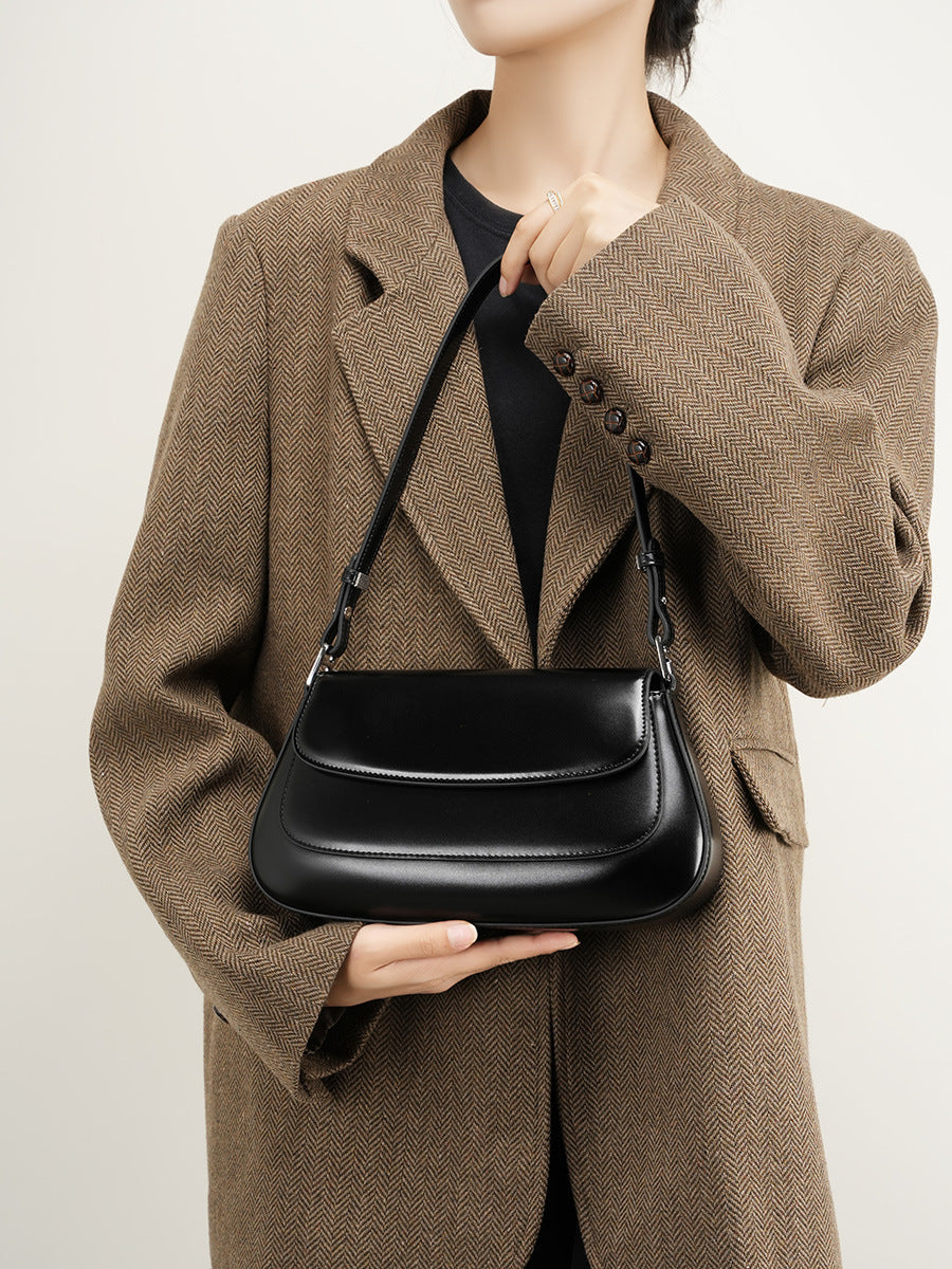 Side profile of the black leather baguette bag showing its compact depth