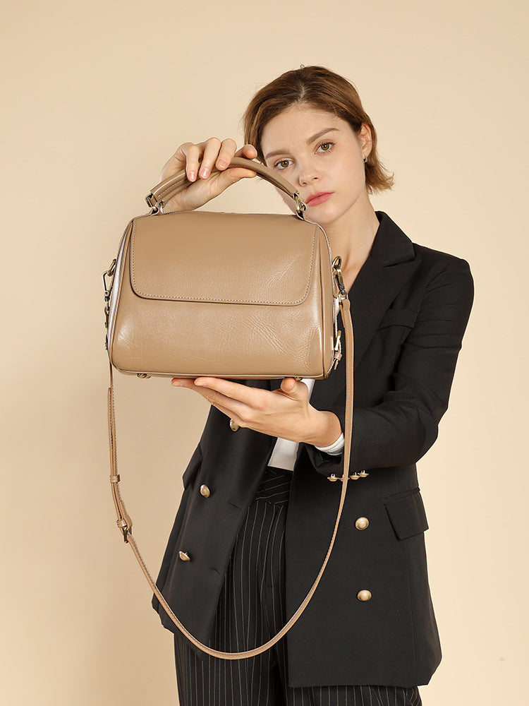 Apricot leather Boston bag held by model in black pinstripe suit