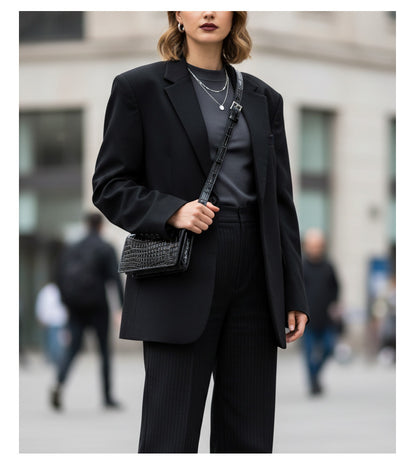 Black textured belt bag styled across the body with tailored clothing