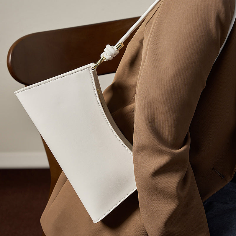 Cream white leather underarm bag styled with a tan blazer in a lifestyle shot