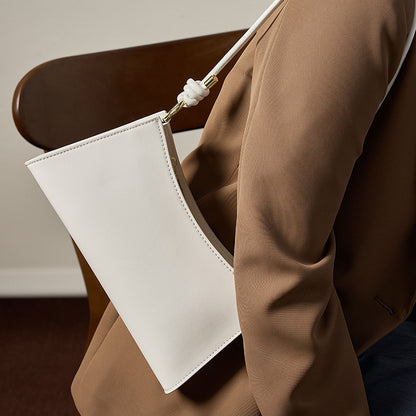Cream white leather underarm bag styled with a tan blazer in a lifestyle shot