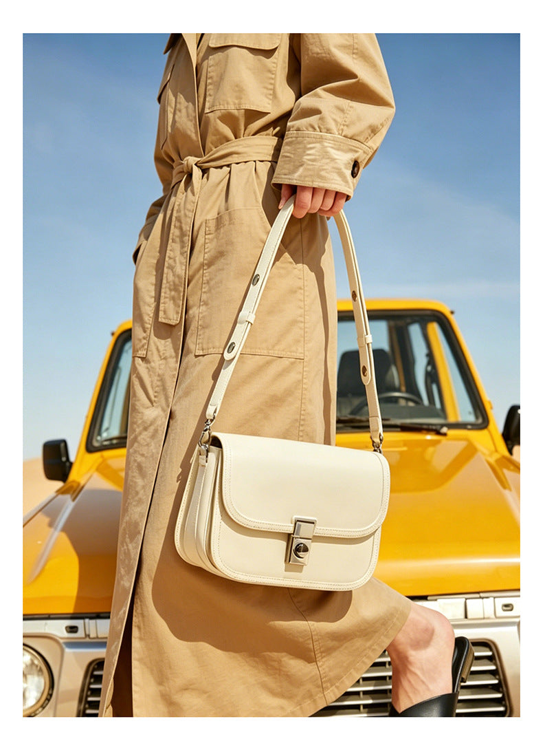 Off-white leather messenger bag held in front of a yellow vehicle