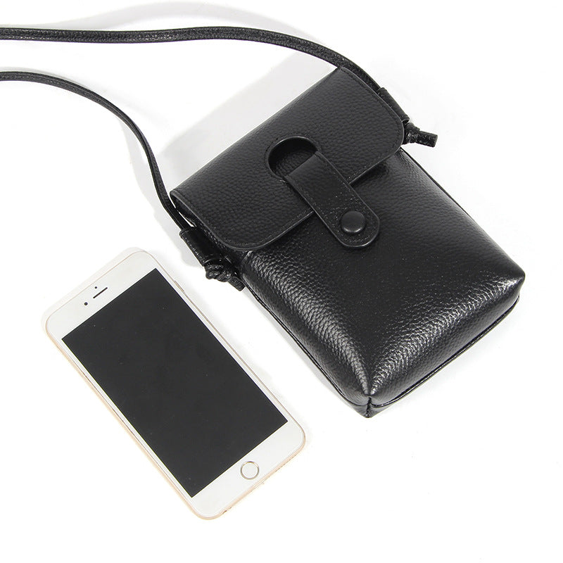 Black pebbled leather phone bag shown next to smartphone for size reference