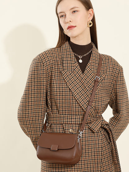 Front view of model with brown leather crossbody bag worn as shoulder bag