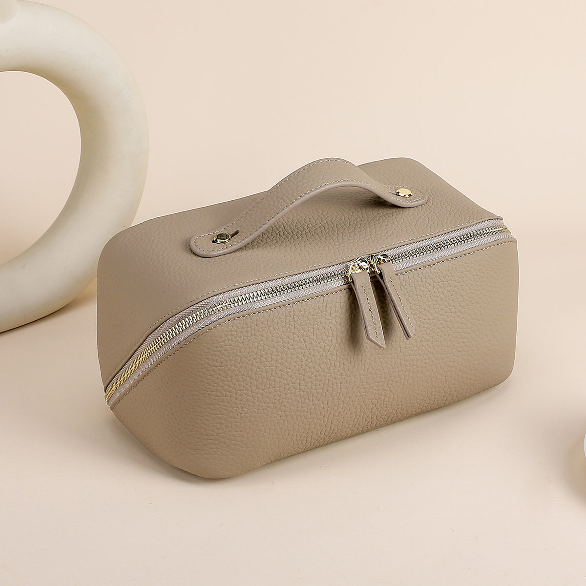 Gray leather cosmetic pouch with textured exterior and zip closure