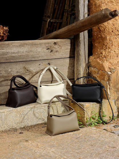Four colorways of the pebbled leather pillow bag on rustic stone steps