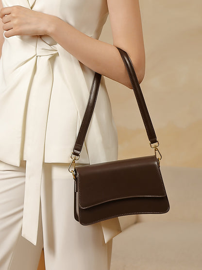 Editorial shot of brown leather shoulder bag paired with cream tie-waist top