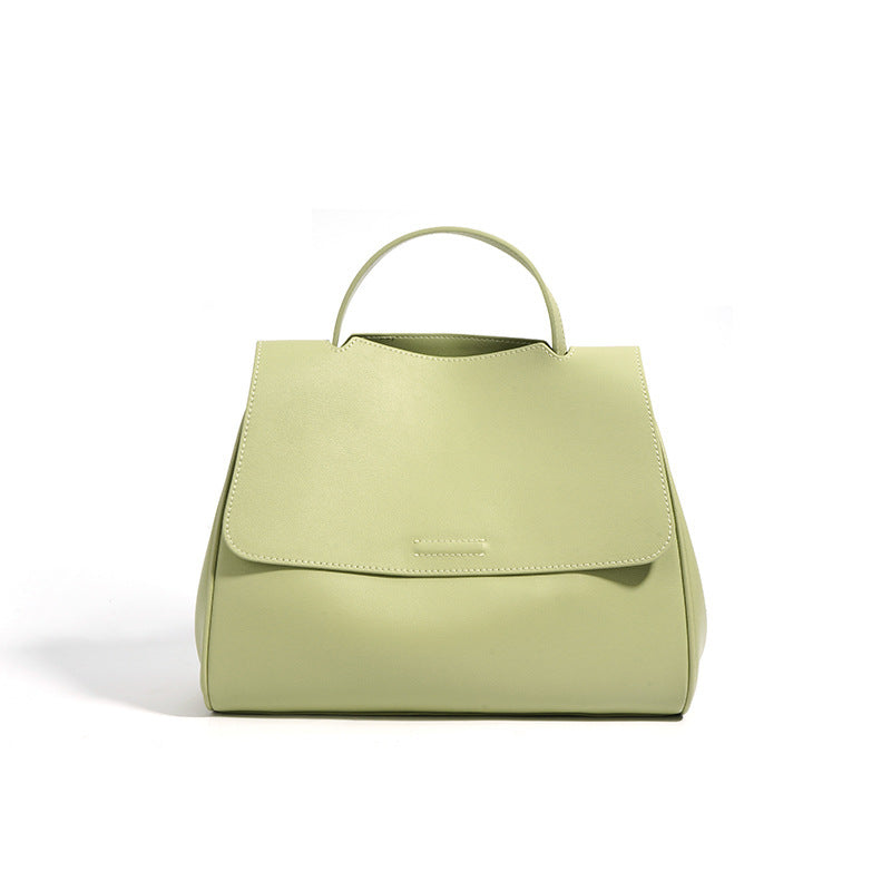 Green cowhide leather top-handle bag with flap closure on white background
