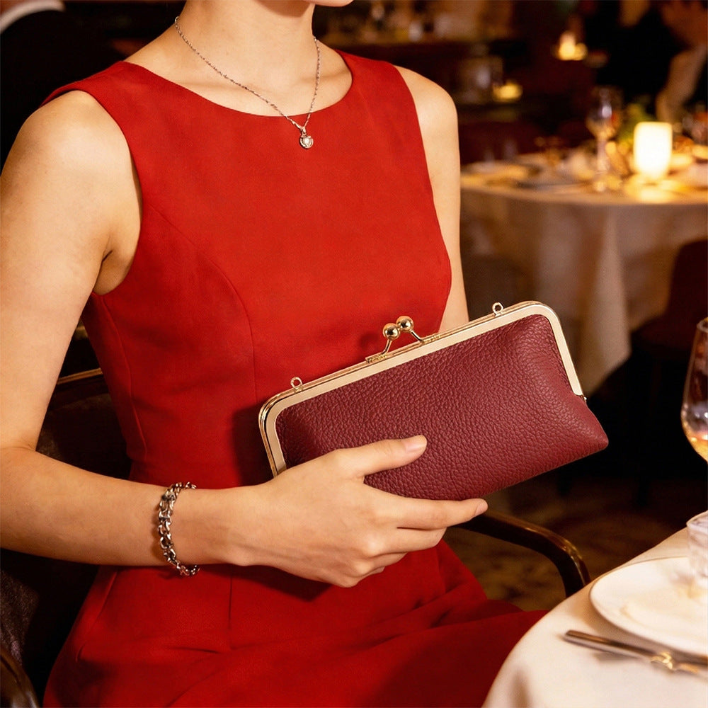 Wine red frame clutch held at an evening table