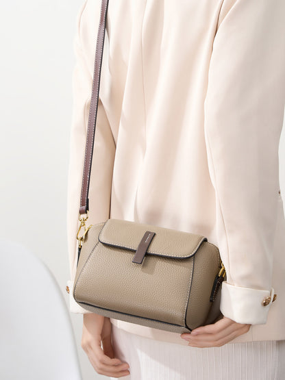 Model holding khaki shell crossbody bag at the hip with the strap shown long