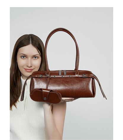 Model in cream top presenting brown leather barrel tote