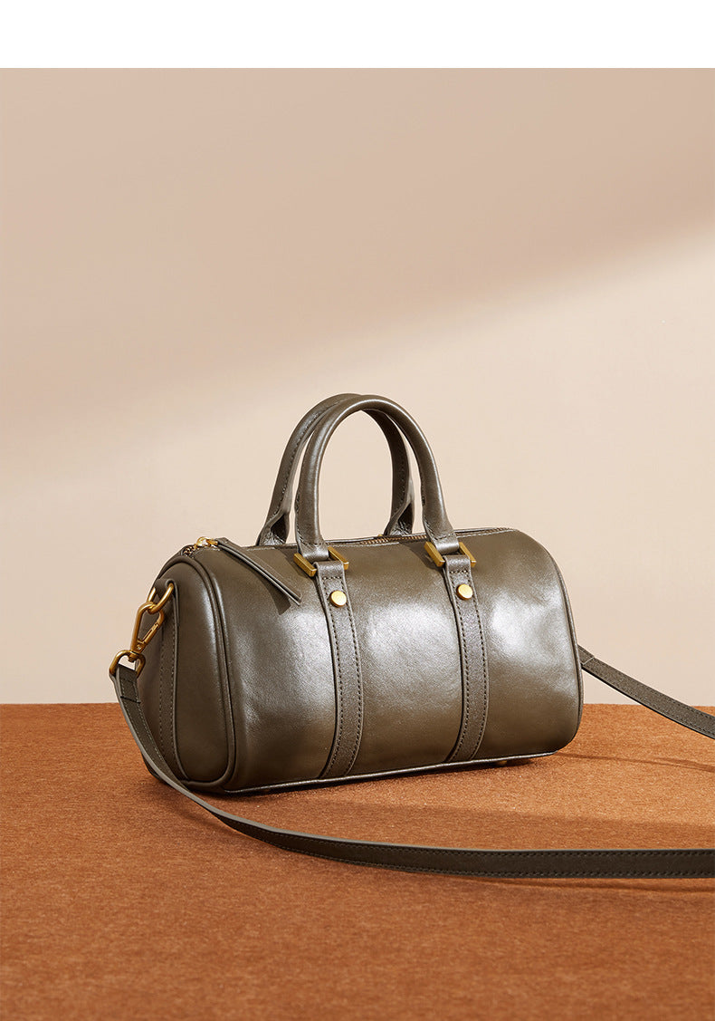 Olive green Boston bag with top handle and detachable strap on neutral surface