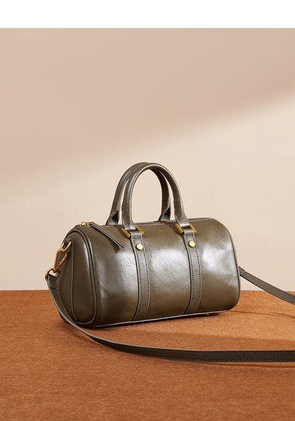 Olive green Boston bag with top handle and detachable strap on neutral surface