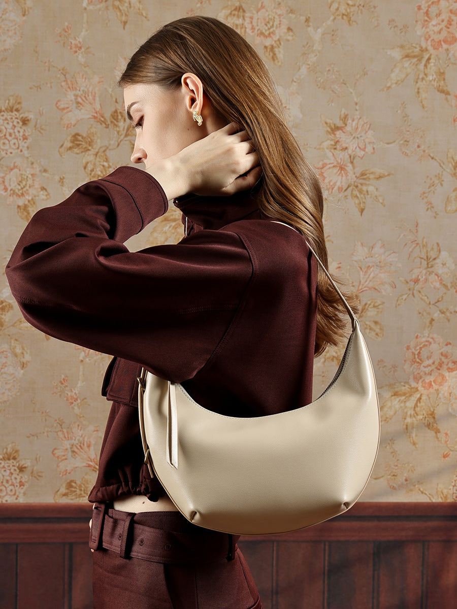 Beige crescent bag worn on shoulder