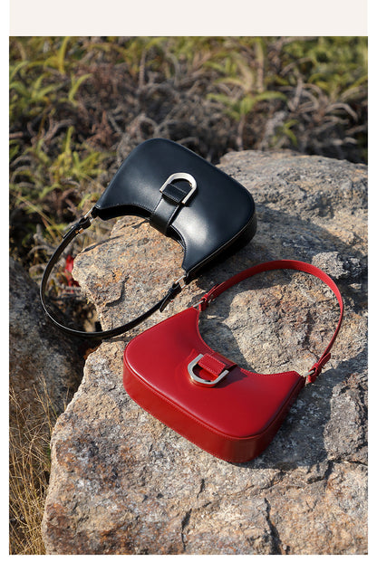 Black and red shoulder bags placed on rock outdoors