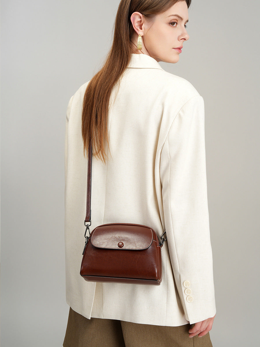 Side view of model with dark brown crossbody bag hanging at hip