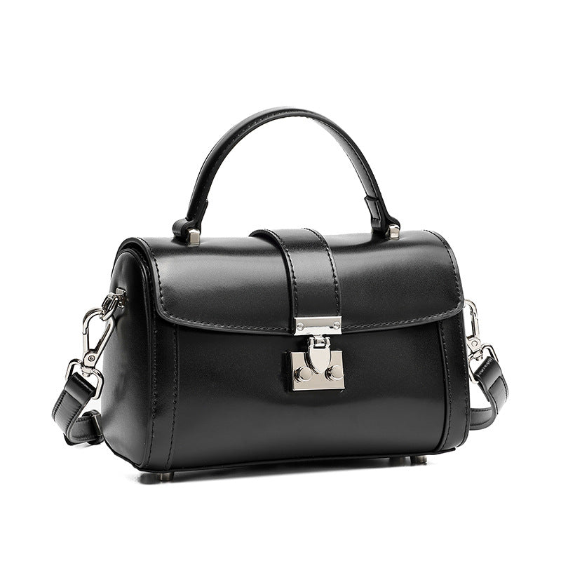Black cowhide leather mini box crossbody bag with lock clasp on white background
