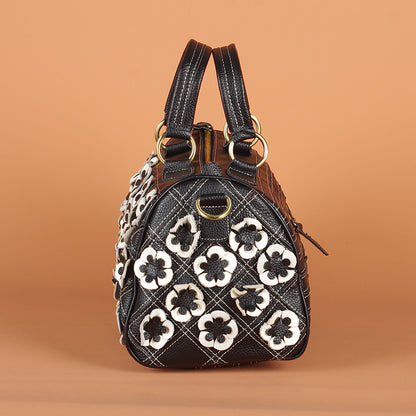 End panel view of black cowhide bag with raised flower details