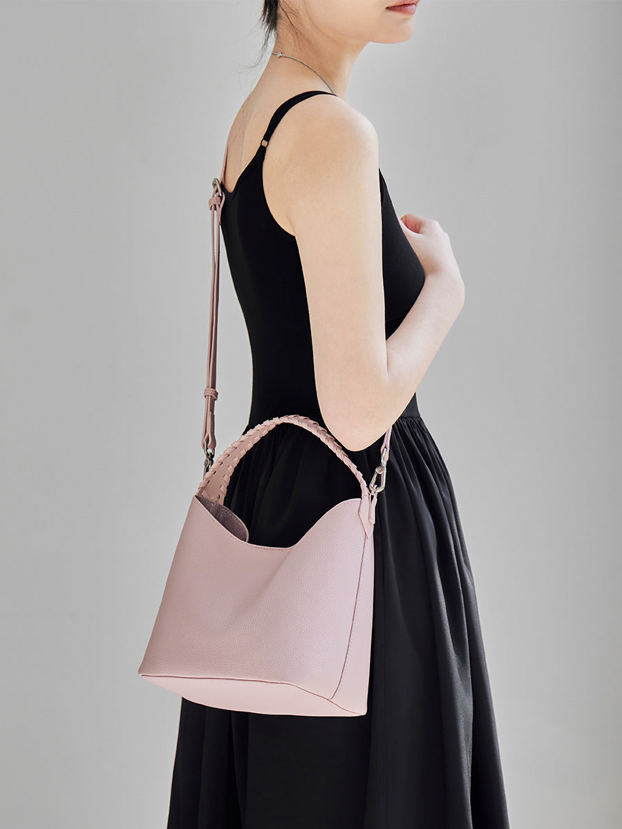 Pink leather bucket bag worn crossbody on a removable long strap