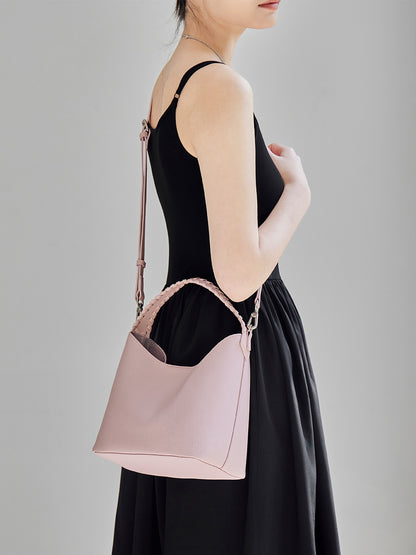 Pink leather bucket bag worn crossbody on a removable long strap