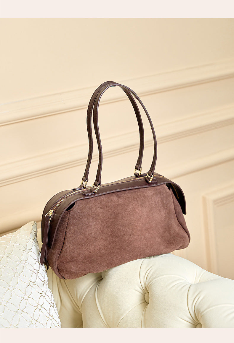 Brown suede shoulder bag displayed on a sofa