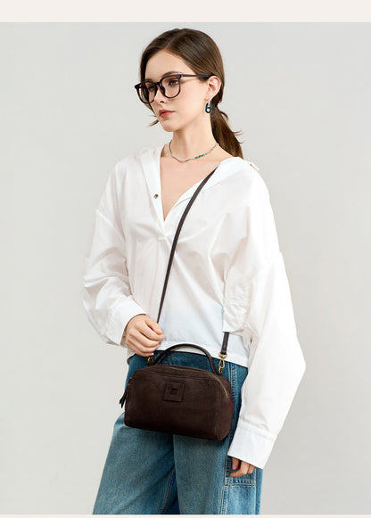 Model wearing the bag crossbody with its top handle visible