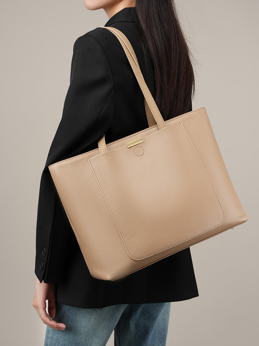 Model carrying apricot leather tote bag over the shoulder while wearing a black blazer
