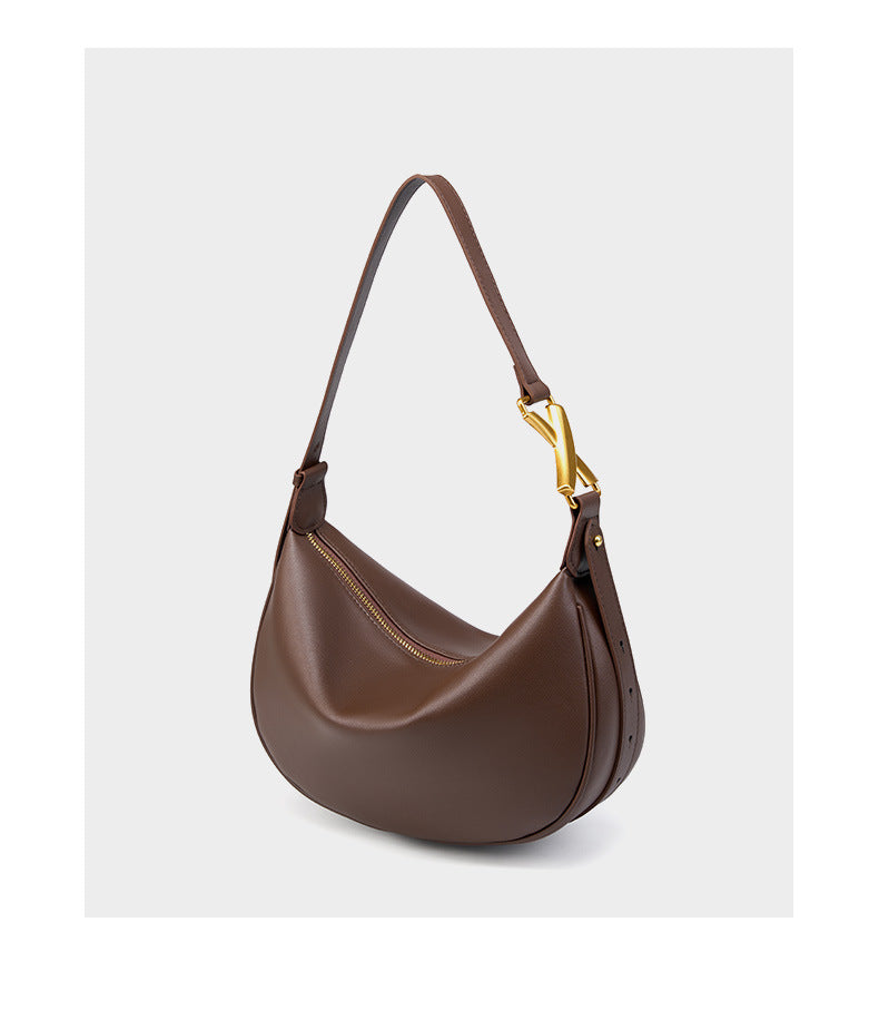 Coffee brown cowhide crescent underarm bag with gold-tone X buckle on a white background