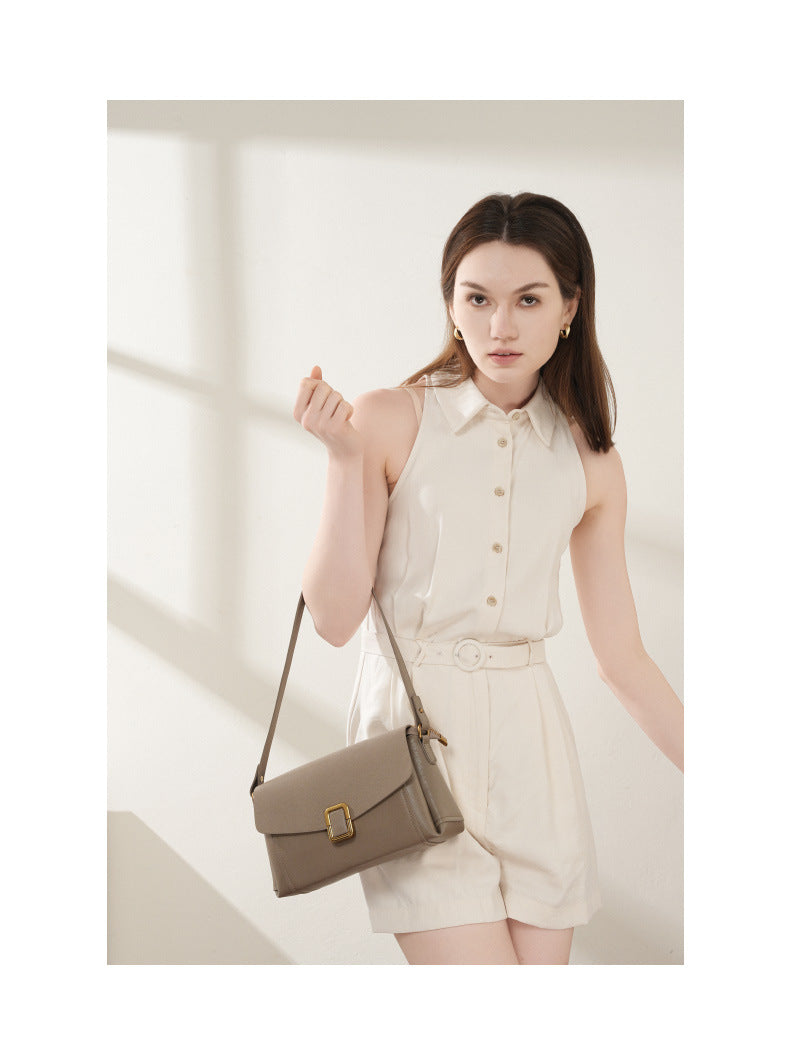 Model wearing gray cowhide leather crossbody bag with cream sleeveless outfit