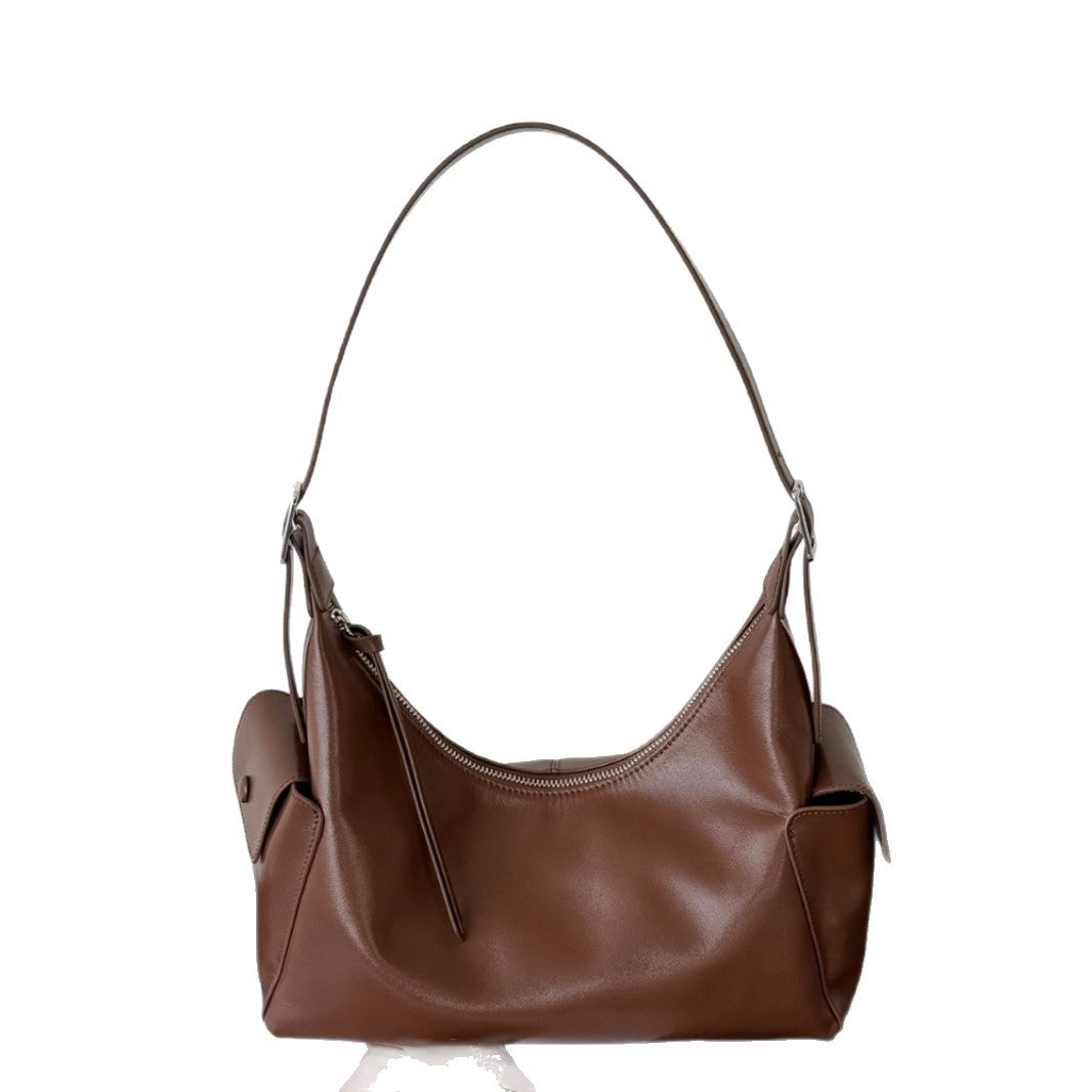 Model holding the brown bag by its shoulder strap