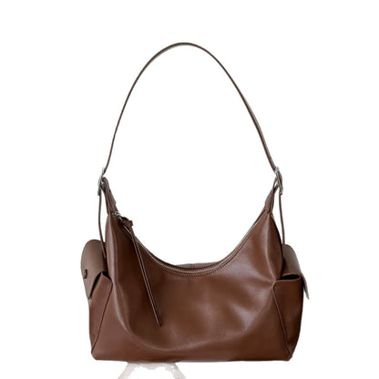 Model holding the brown bag by its shoulder strap