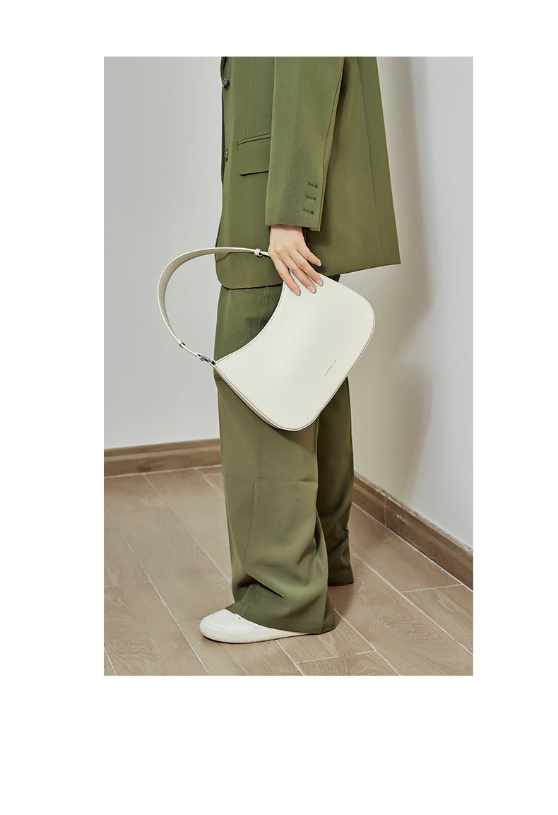 Model carrying white cowhide leather underarm shoulder bag with olive green tailored outfit