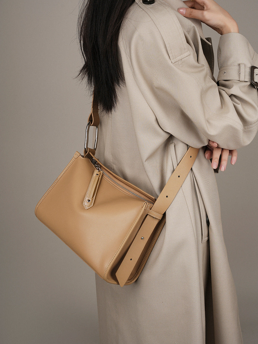 Apricot pillow bag worn crossbody with trench coat