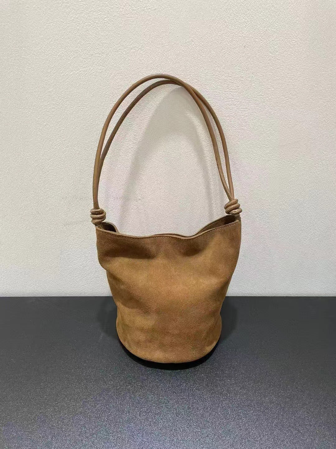 Brown bucket bag shown from the front with long strap
