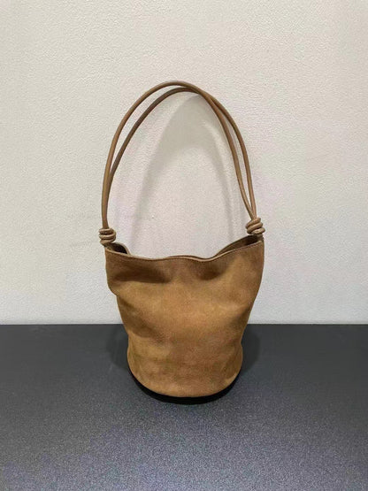 Brown bucket bag shown from the front with long strap