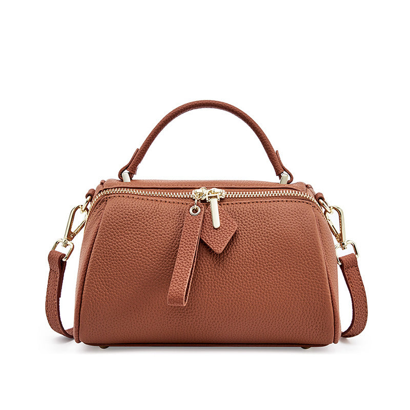 Golden brown top-grain cowhide mini Boston bag with dual zip closure and adjustable strap