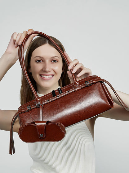 Smiling model holding brown leather barrel bag up to frame her face