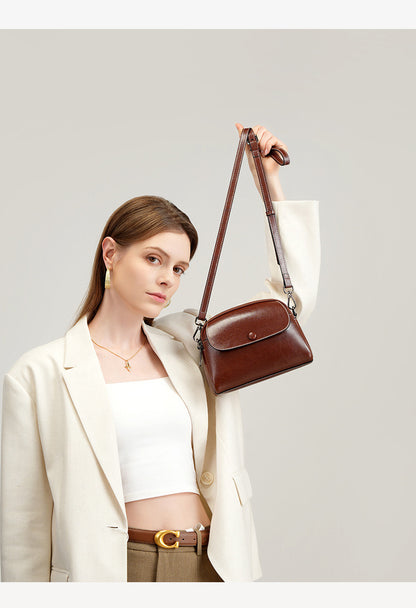 Model lifting brown leather bag by its long strap