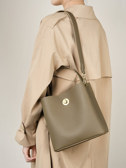 Khaki bucket bag worn as crossbody with trench coat