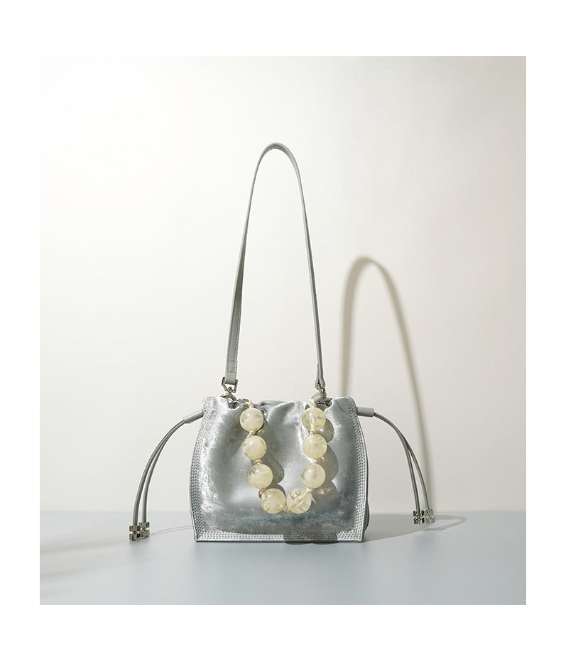 Silver mini bucket bag shown front-facing with straps hanging down