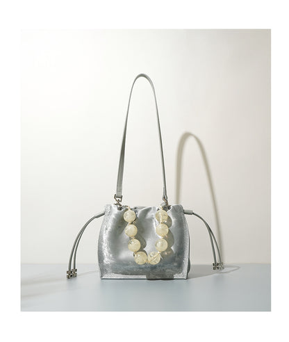Silver mini bucket bag shown front-facing with straps hanging down