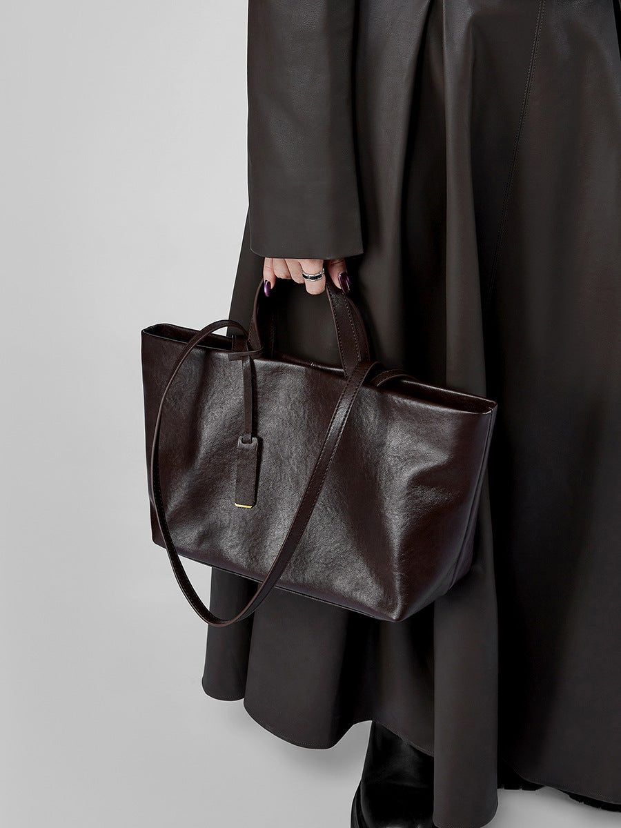 Model wearing dark brown leather tote with long coat