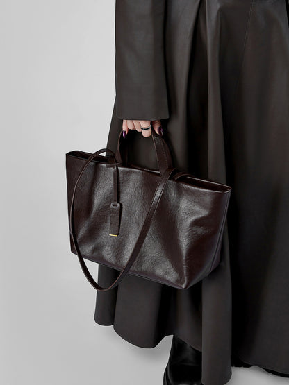 Model wearing dark brown leather tote with long coat