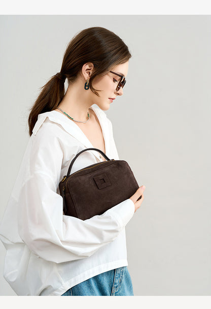 Model carrying the dark brown rectangular bag in her arms
