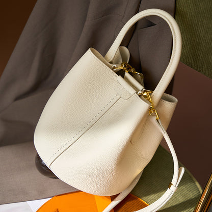 Off-white bucket bag displayed on chair showing gold-tone hardware