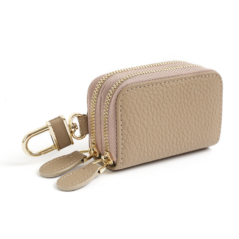 Light gray cowhide leather key case pouch with double zipper and gold-tone rotating clip on white background