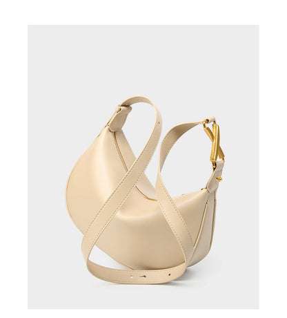 Off-white cowhide crescent underarm bag with adjustable shoulder strap laid flat
