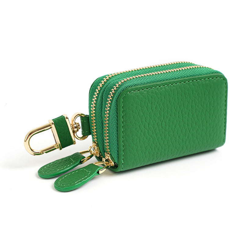 Green cowhide leather key case pouch with double zipper and gold-tone rotating clip on white background