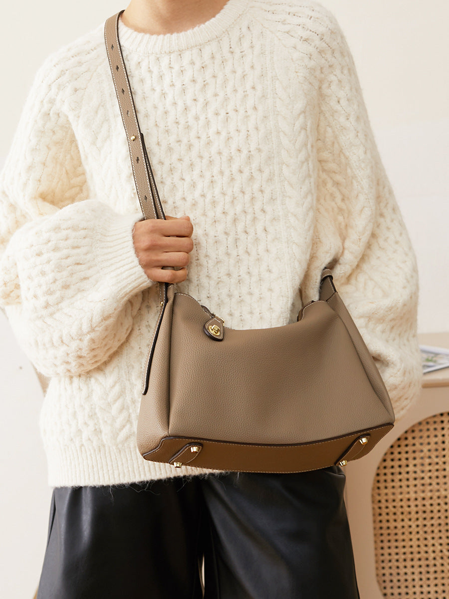 Close-up of model holding dark gray leather shoulder bag by top handle