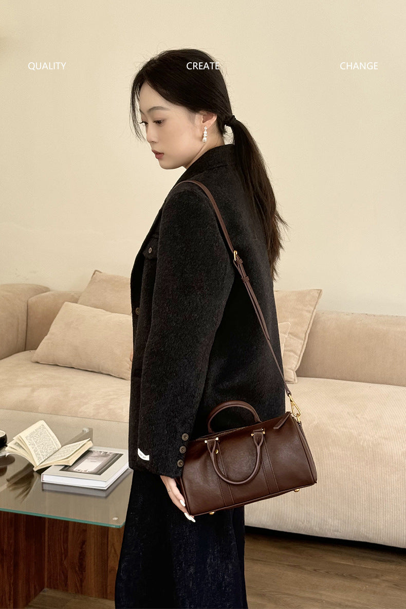 Side view of dark brown Boston bag worn crossbody in living room scene